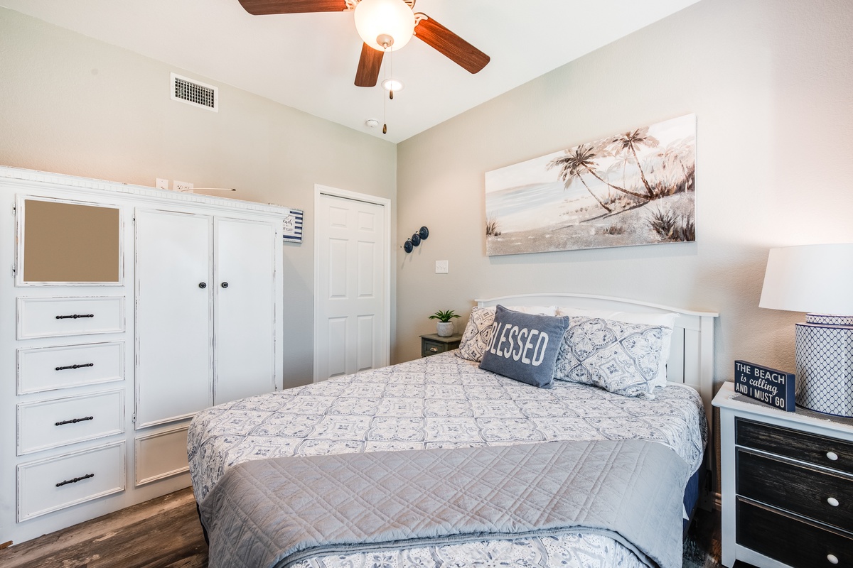 Drift off in your coastal-themed bedroom with tropical artwork, plush bedding, and a gentle ceiling fan creating the perfect sleep sanctuary.