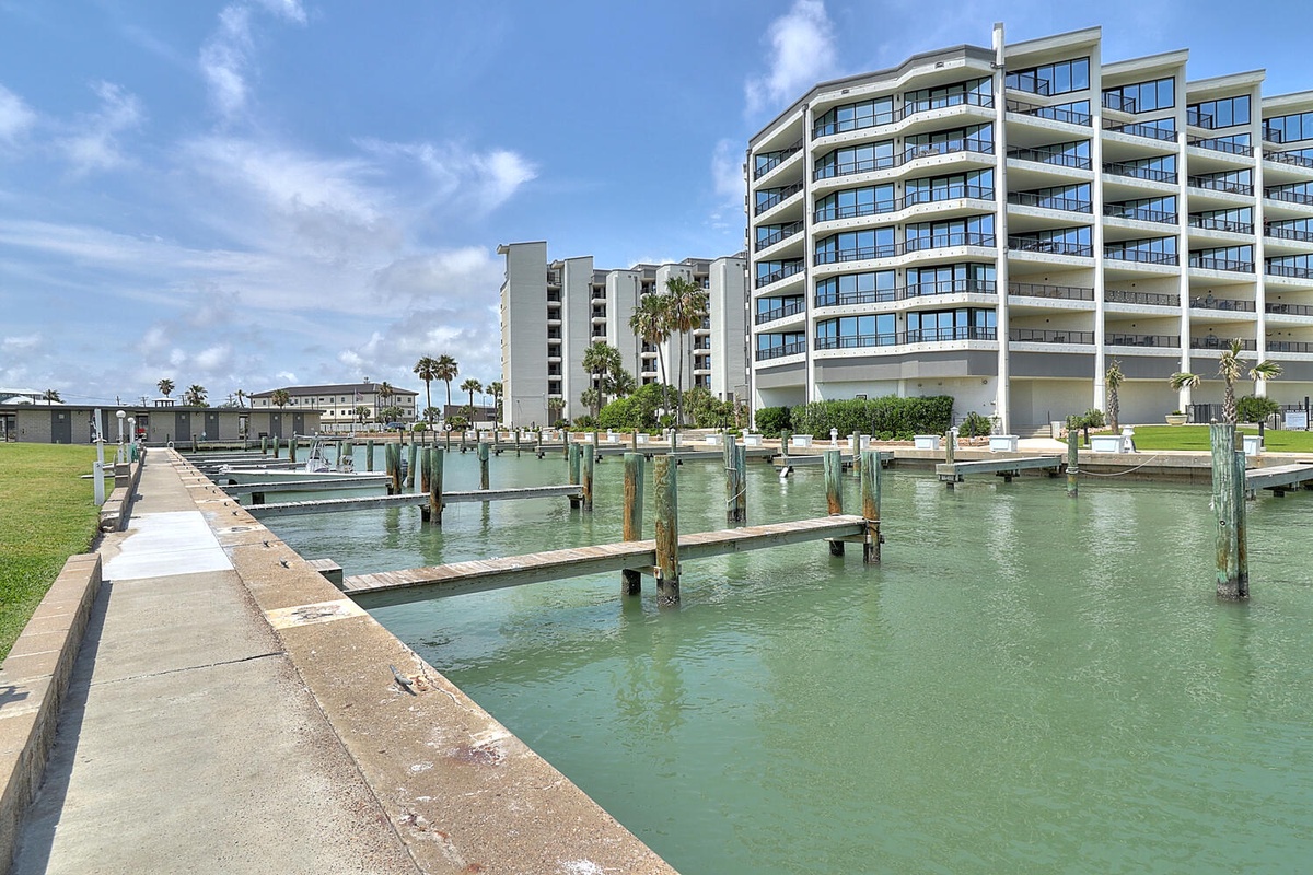 Modern waterfront property with private marina and boat docks in a tropical coastal setting with palm trees.
