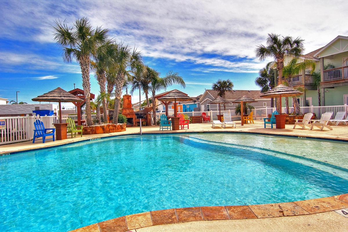 Tropical pool area with colorful lounge chairs and palm-lined deck for perfect poolside relaxation.