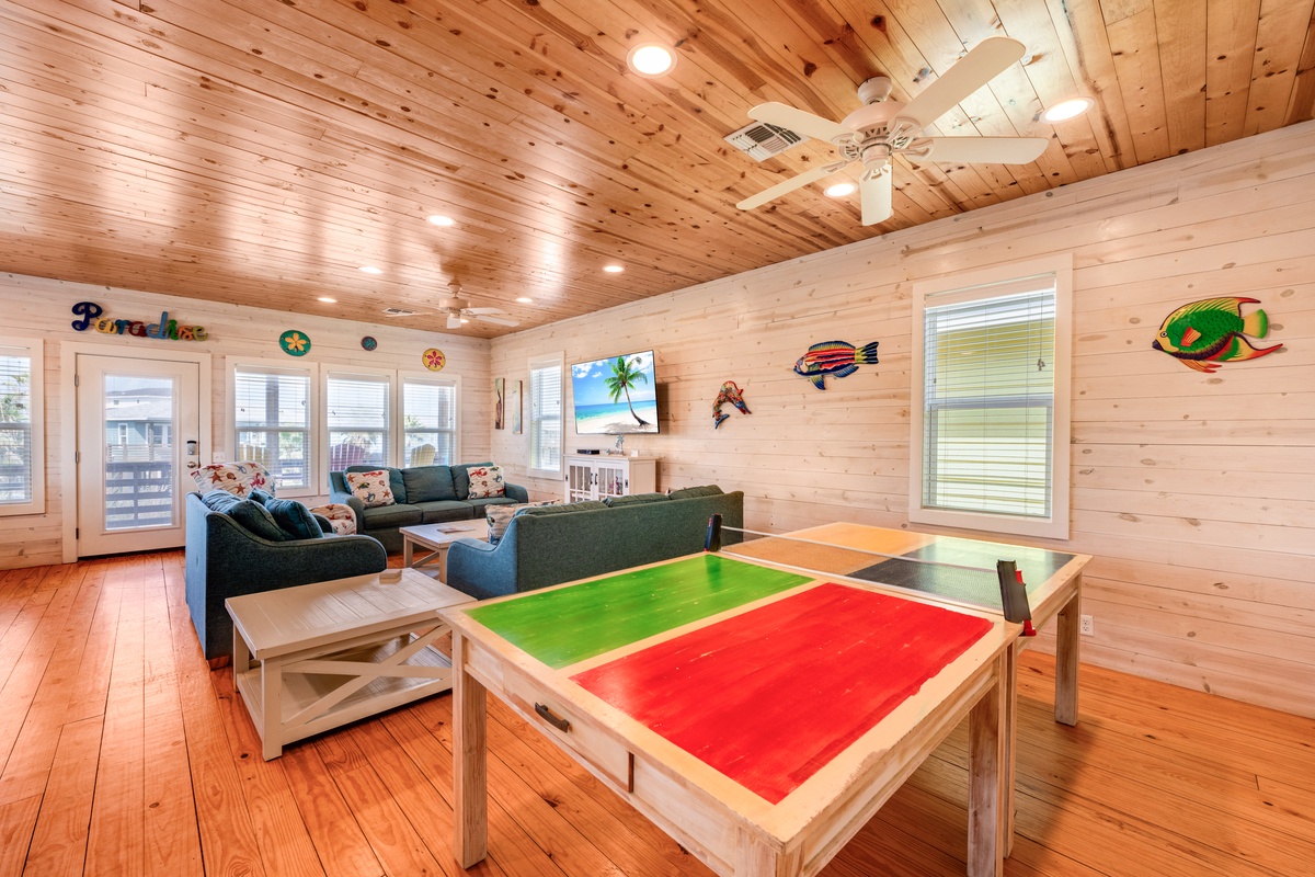 Gather around the colorful game table for family fun, or sink into plush sectional seating beneath warm wood beams and coastal decor.