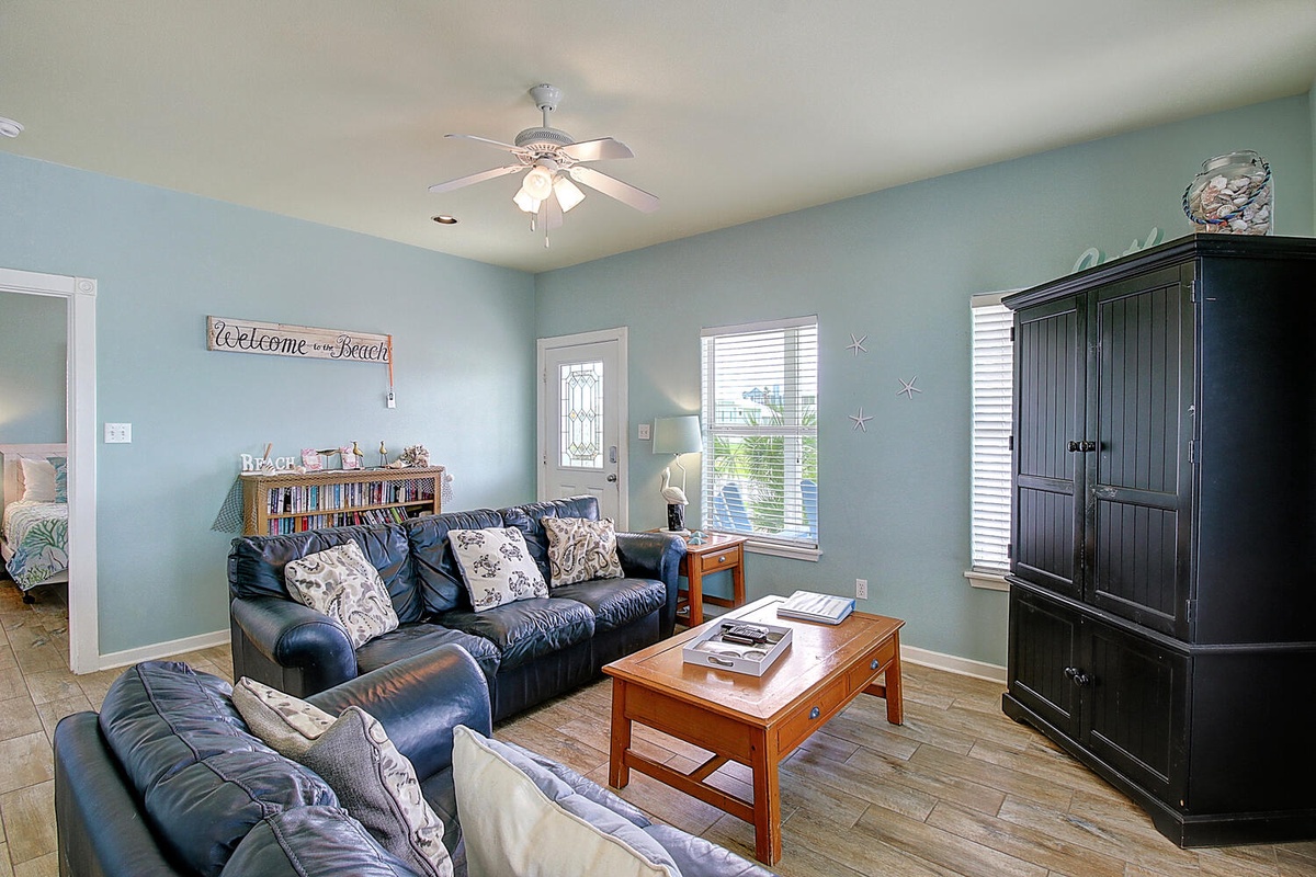 Settle into coastal comfort where soft blue walls and leather seating create your perfect retreat for evening relaxation.
