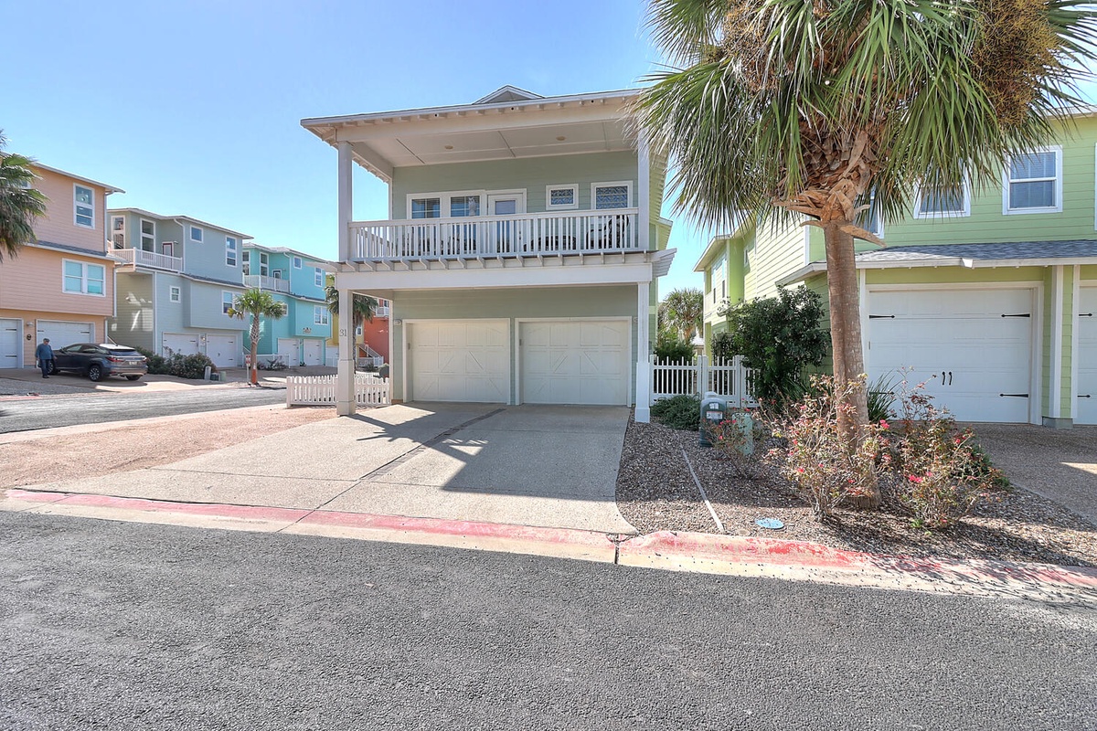 Charming coastal home with covered balcony and two-car garage in colorful beachside neighborhood.