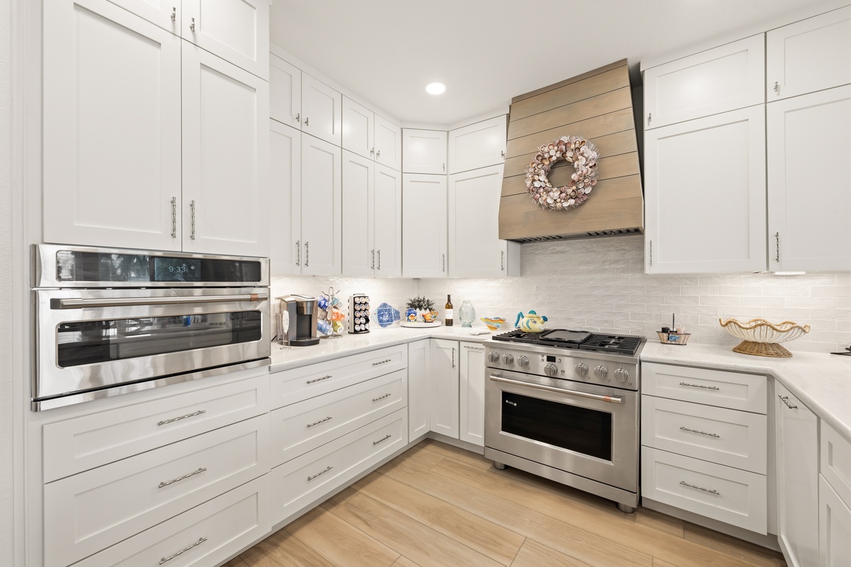 Step into your bright, fully equipped kitchen where crisp white cabinetry and gleaming stainless steel appliances await. Picture yourself preparing delicious meals at the spacious counters, with everything you need right at your fingertips.