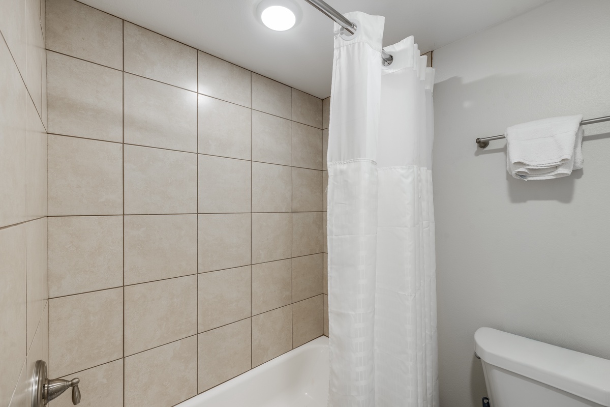 Step into your clean, modern bathroom with fresh towels and a spacious shower-tub combo for relaxing baths or quick rinses.