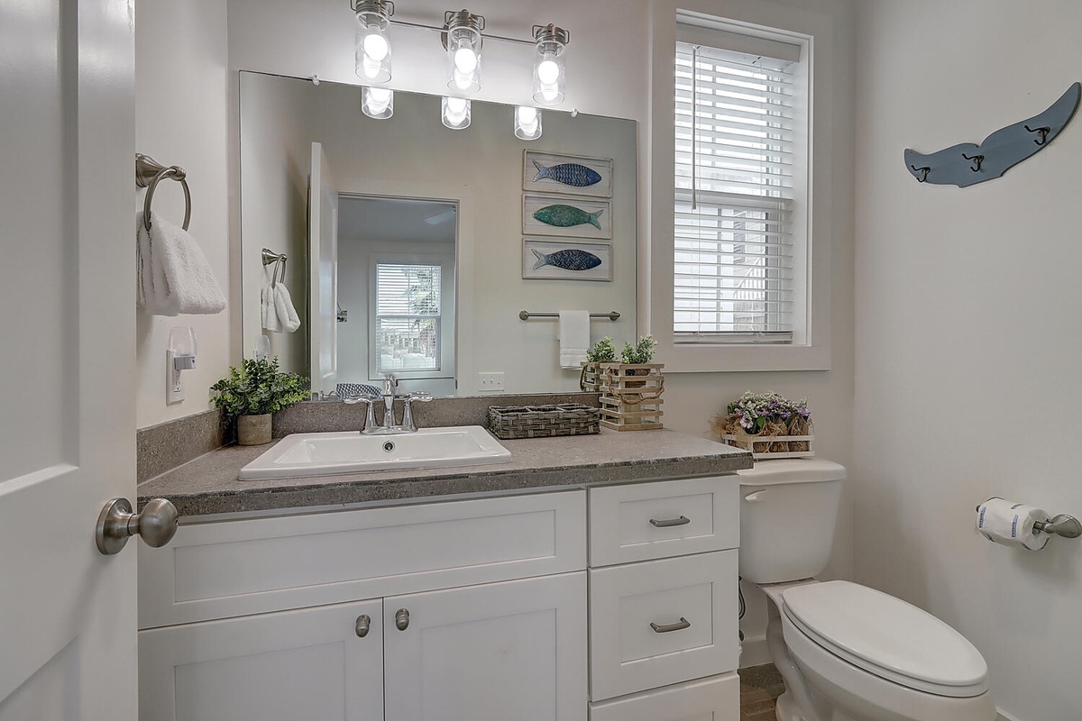 Freshen up in this beautifully appointed bathroom with granite counters, charming coastal touches, and plenty of natural light.