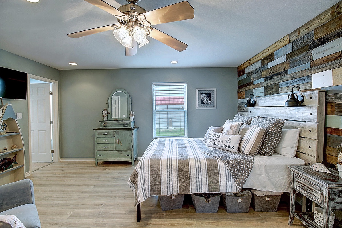 Unwind in your coastal-inspired bedroom with rustic wood accent wall and nautical touches for peaceful sleep.