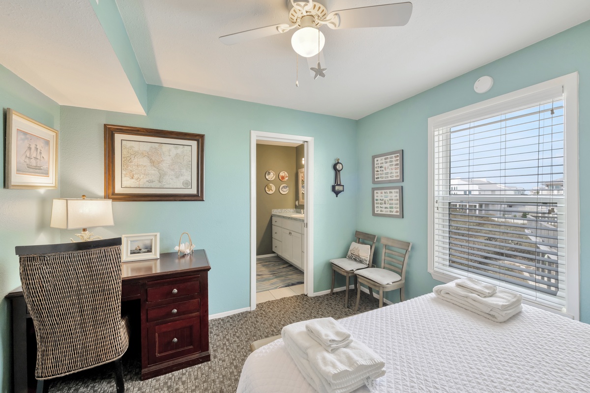 Unwind in your coastal-themed bedroom with soft blue walls, nautical art, and a comfortable workspace overlooking the surrounding area.