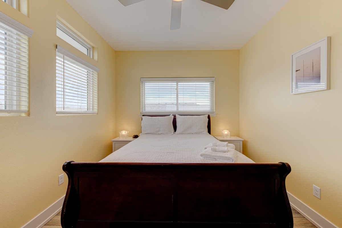 Drift into restful sleep in this cozy bedroom with soft natural light filtering through blinds and plush towels awaiting your arrival.
