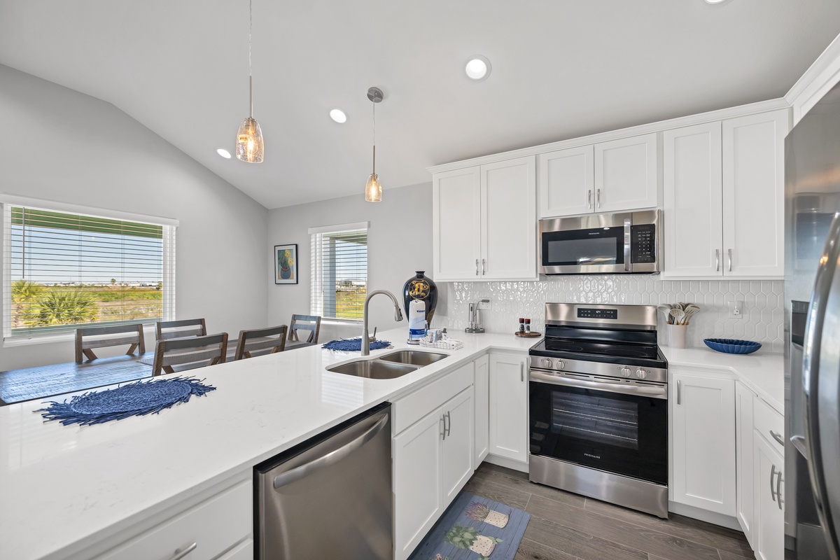 Cook with ease in your fully equipped modern kitchen, featuring white cabinetry, stainless appliances, and a breakfast bar for casual dining.