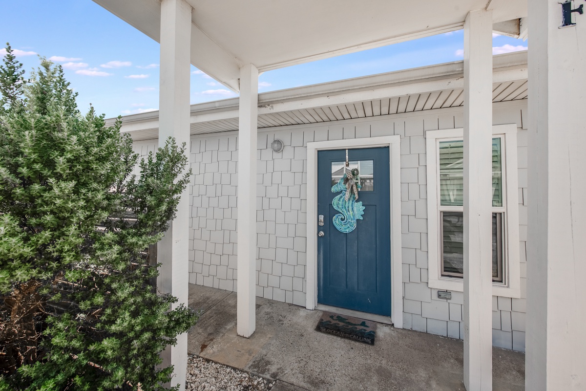 Charming front entrance with coastal blue door and welcoming covered porch for your arrival.