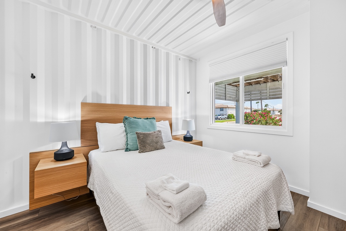 Sink into crisp linens and let the gentle ceiling fan lull you to rest in this serene second bedroom, where warm wood tones and soft natural light create your perfect retreat in your queen bed.