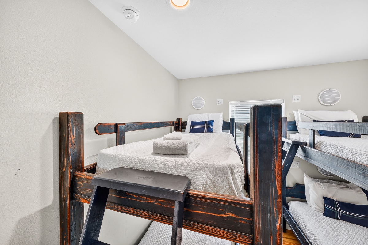 Your unique bunk setup features sturdy, rustic wooden frames with fresh white bedding and nautical-inspired pillows—perfect for a cozy group escape with a touch of maritime charm.