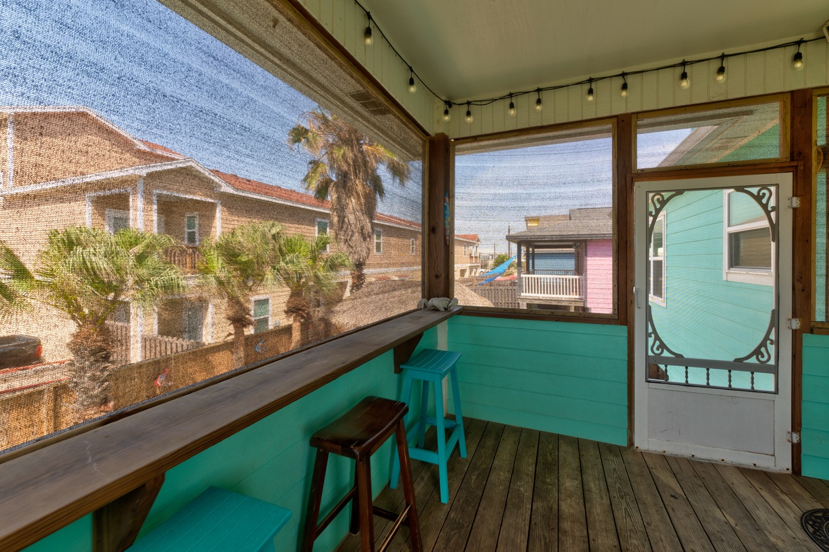 Relax on your screened balcony with turquoise accents, wooden floors, and charming neighborhood views through large windows.