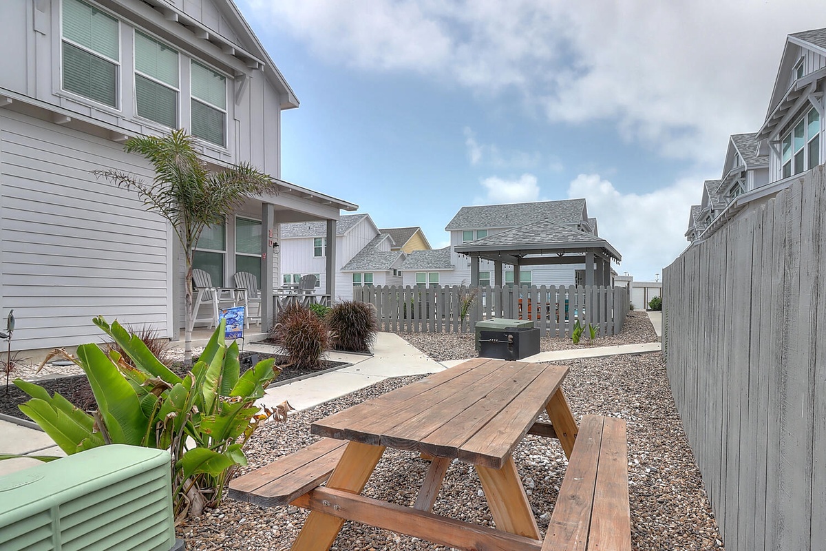 Relax at your private picnic table surrounded by tropical plants and coastal charm in this peaceful backyard retreat.