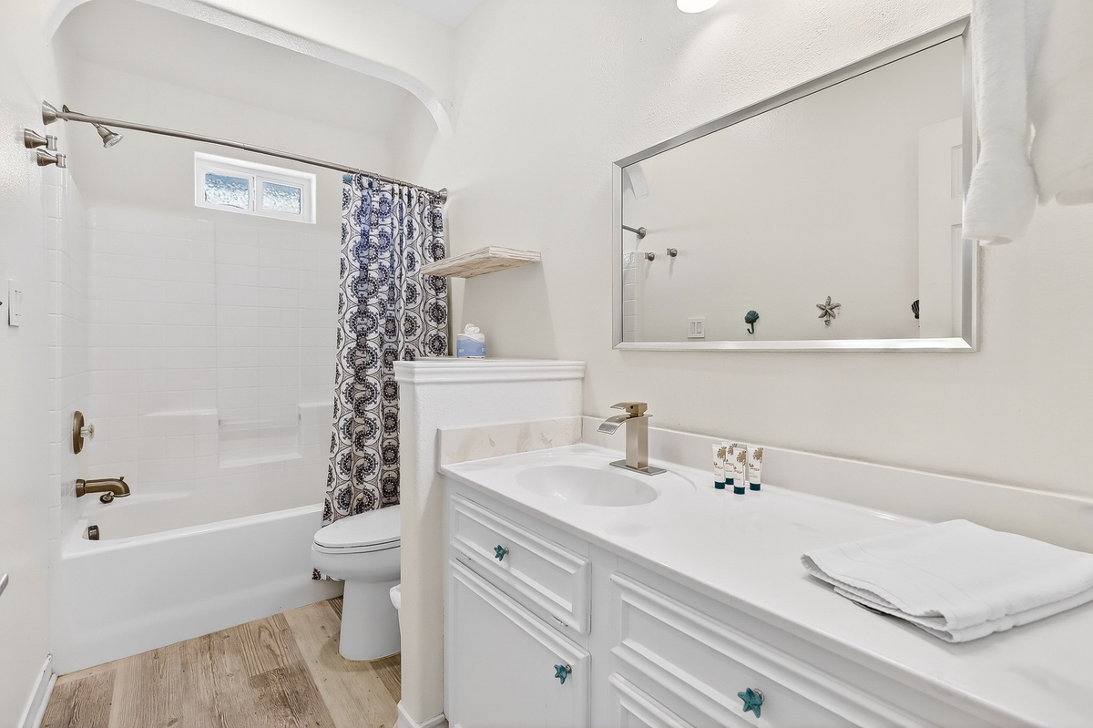 Refresh in your pristine white bathroom with elegant fixtures, spacious vanity, and charming nautical touches that make your morning routine feel luxurious.