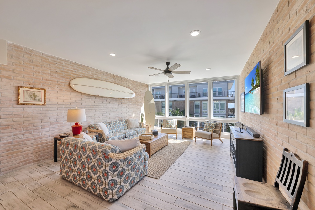 Relax in this stylish living space with exposed brick walls, comfortable seating, and large windows flooding the room with natural light.