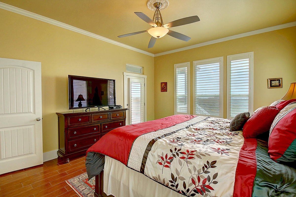 Unwind in your peaceful retreat with colorful linens, ceiling fan, and stunning views through multiple windows.