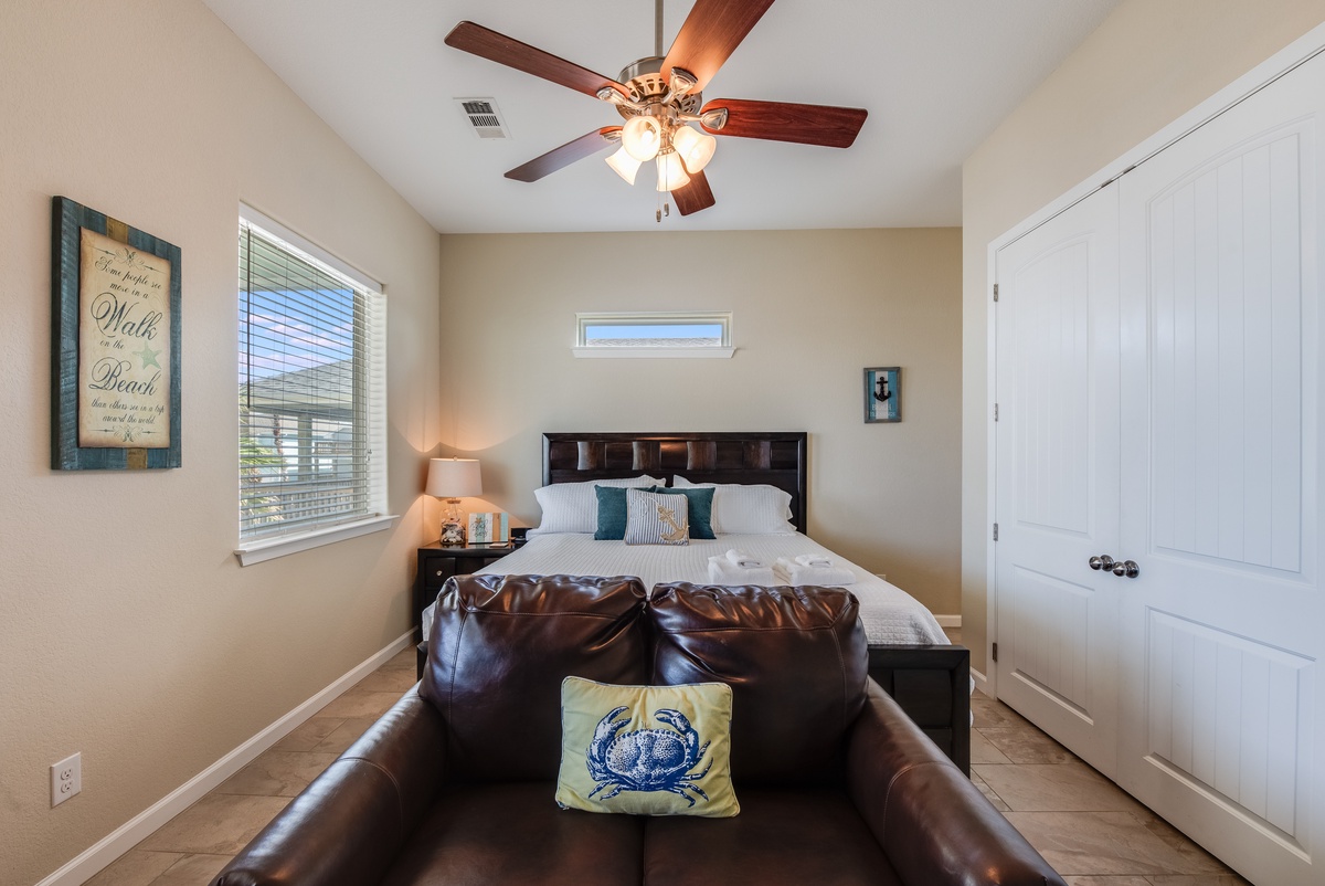 Unwind in your cozy bedroom featuring a plush king bed, ceiling fan for comfort, and coastal decor that creates the perfect retreat.