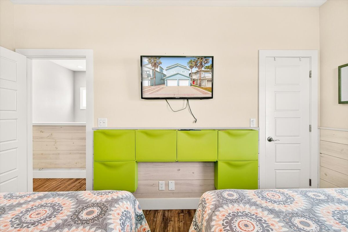 Unwind in your modern bedroom with twin beds, vibrant built-in storage, and wall-mounted TV for cozy movie nights.