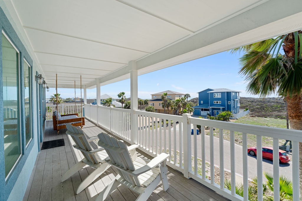 Relax on your private covered balcony with comfortable seating while enjoying views of the coastal neighborhood and palm trees.