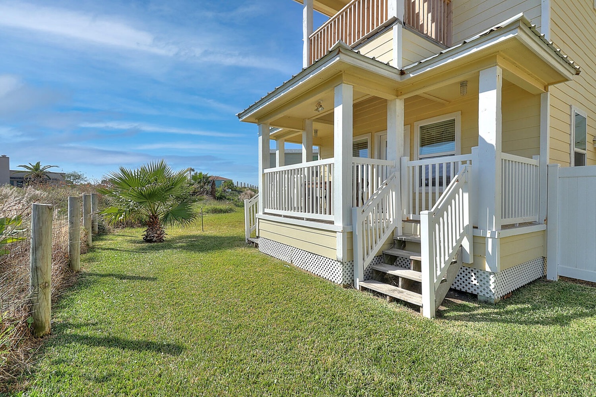 Charming coastal cottage featuring wraparound porch and private yard with tropical palm tree, perfect for seaside getaways.