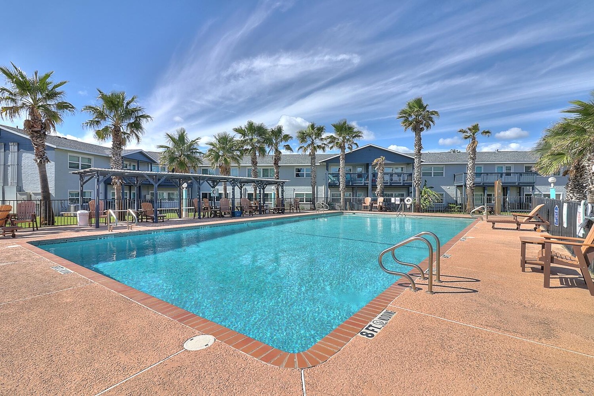 Take a refreshing dip in the sparkling pool surrounded by swaying palm trees and comfortable lounge chairs for your perfect relaxation.