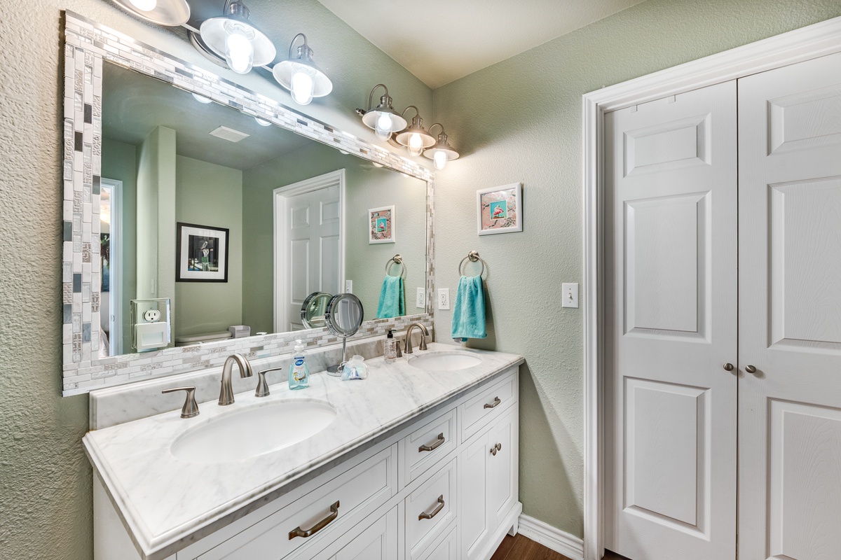 Refresh in this elegant dual-sink bathroom with marble countertops, soft lighting, and calming sage walls—your perfect morning retreat.