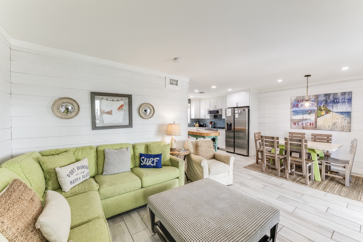 Sink into the cozy green sofa and feel instantly at home in this bright, open-plan space, where coastal charm meets modern comfort for your perfect beach getaway.
