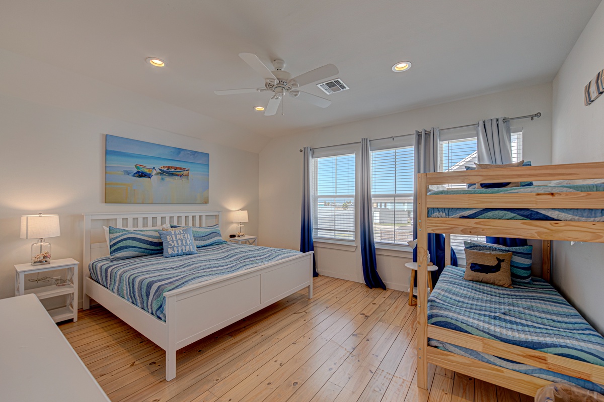 Drift off in your coastal-themed bedroom featuring comfortable beds and charming bunk beds, perfect for families seeking beachside relaxation.