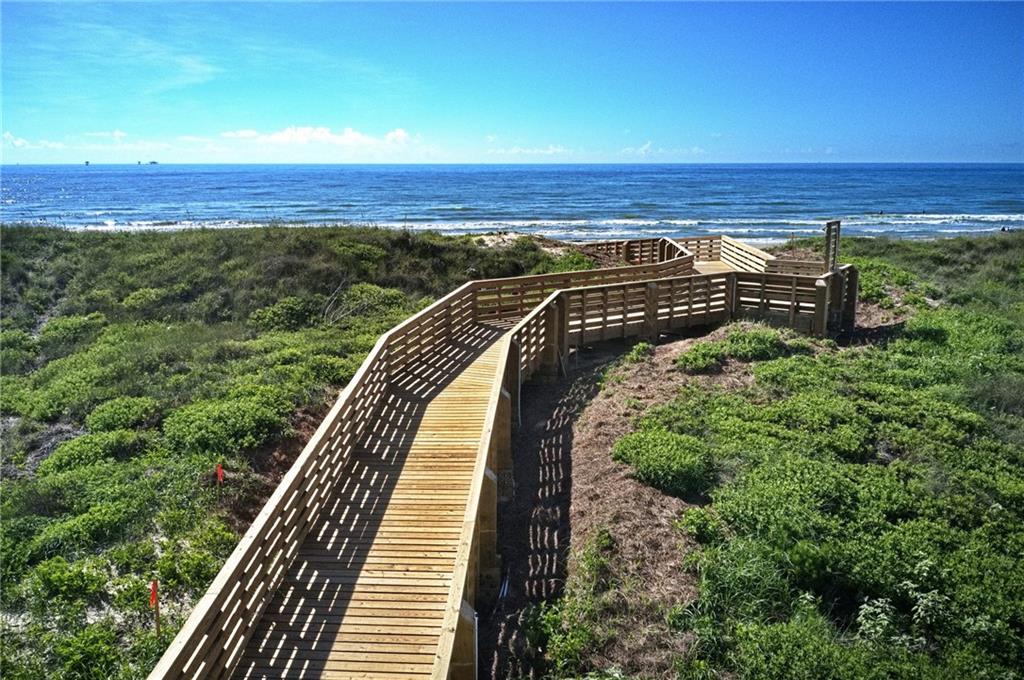 Scenic wooden boardwalk leads through coastal dunes to pristine beach access with expansive ocean views.