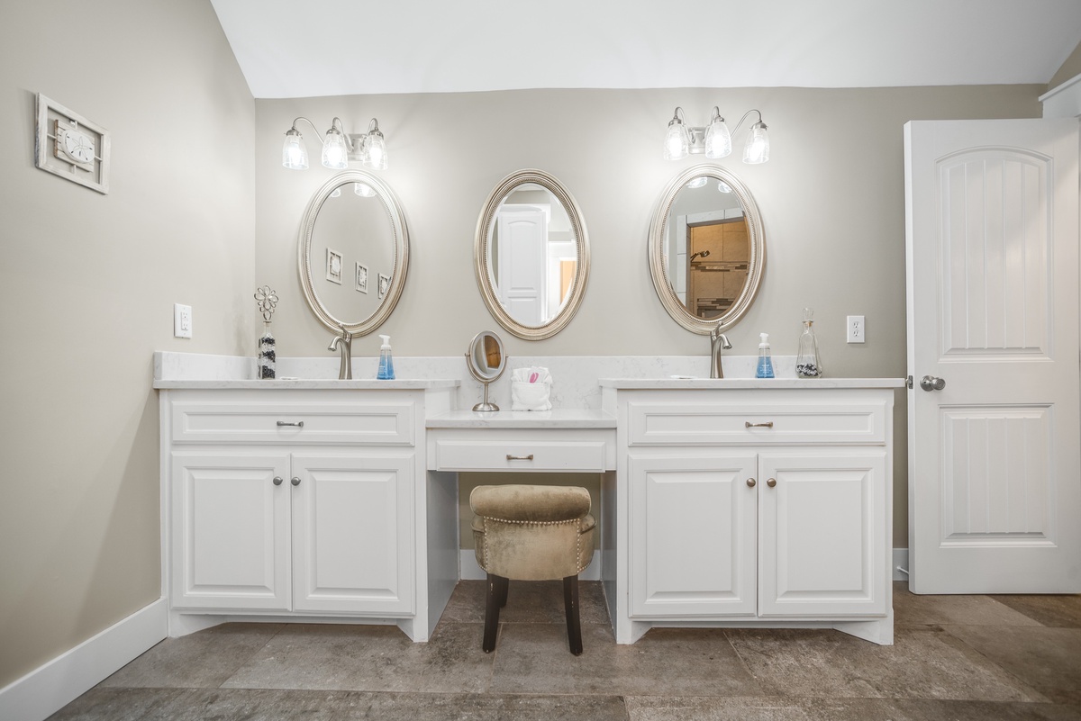 Pamper yourself in this elegant dual-vanity bathroom with professional lighting and a charming makeup station—perfect for your morning routine.