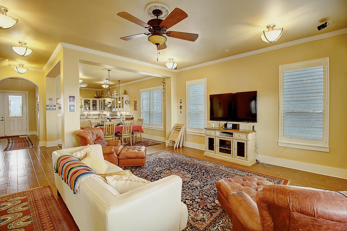 Relax in your spacious living room with plush leather seating, warm lighting, and open kitchen views perfect for gathering.