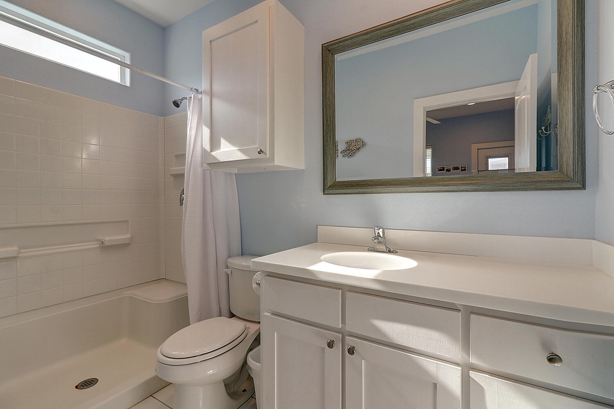 Your private bathroom features a spacious walk-in shower, ample vanity storage, and calming blue walls that create a peaceful retreat.