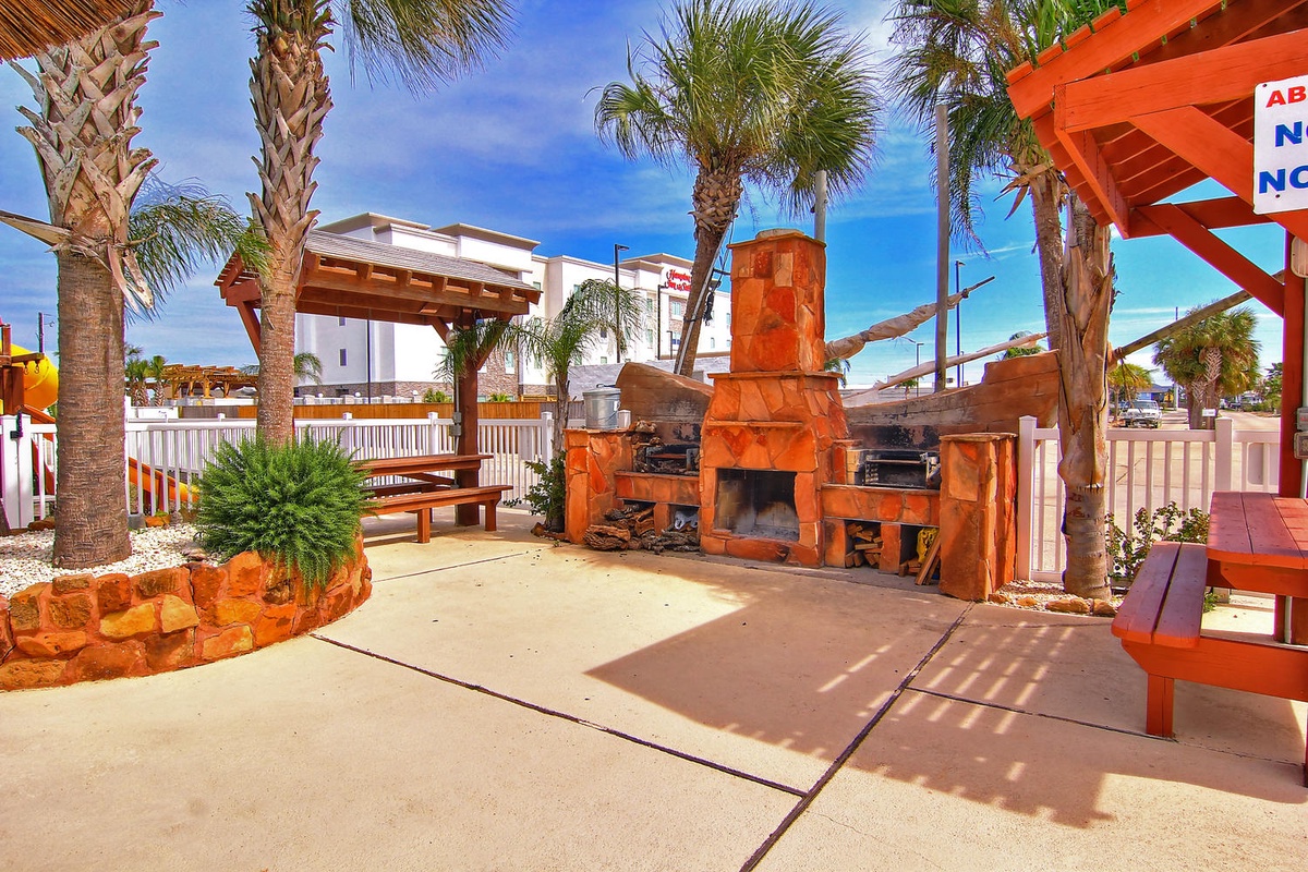 Relax in your private outdoor paradise with a stunning stone fireplace and tropical palms creating the perfect BBQ retreat.