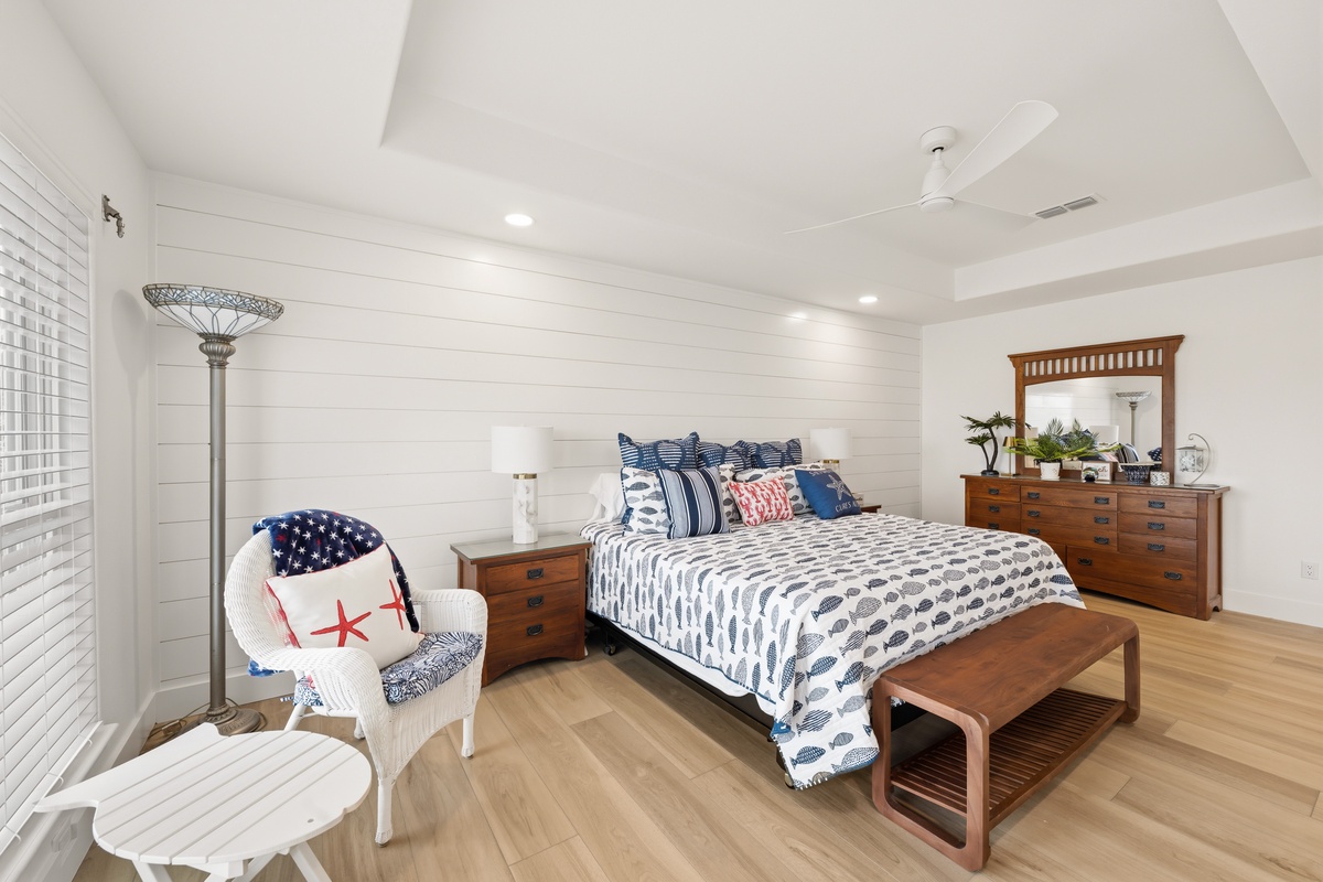 Your spacious coastal-style bedroom features a plush king bed dressed in crisp nautical linens, warm wood furnishings, and a cozy reading nook perfect for unwinding after a day of adventure.