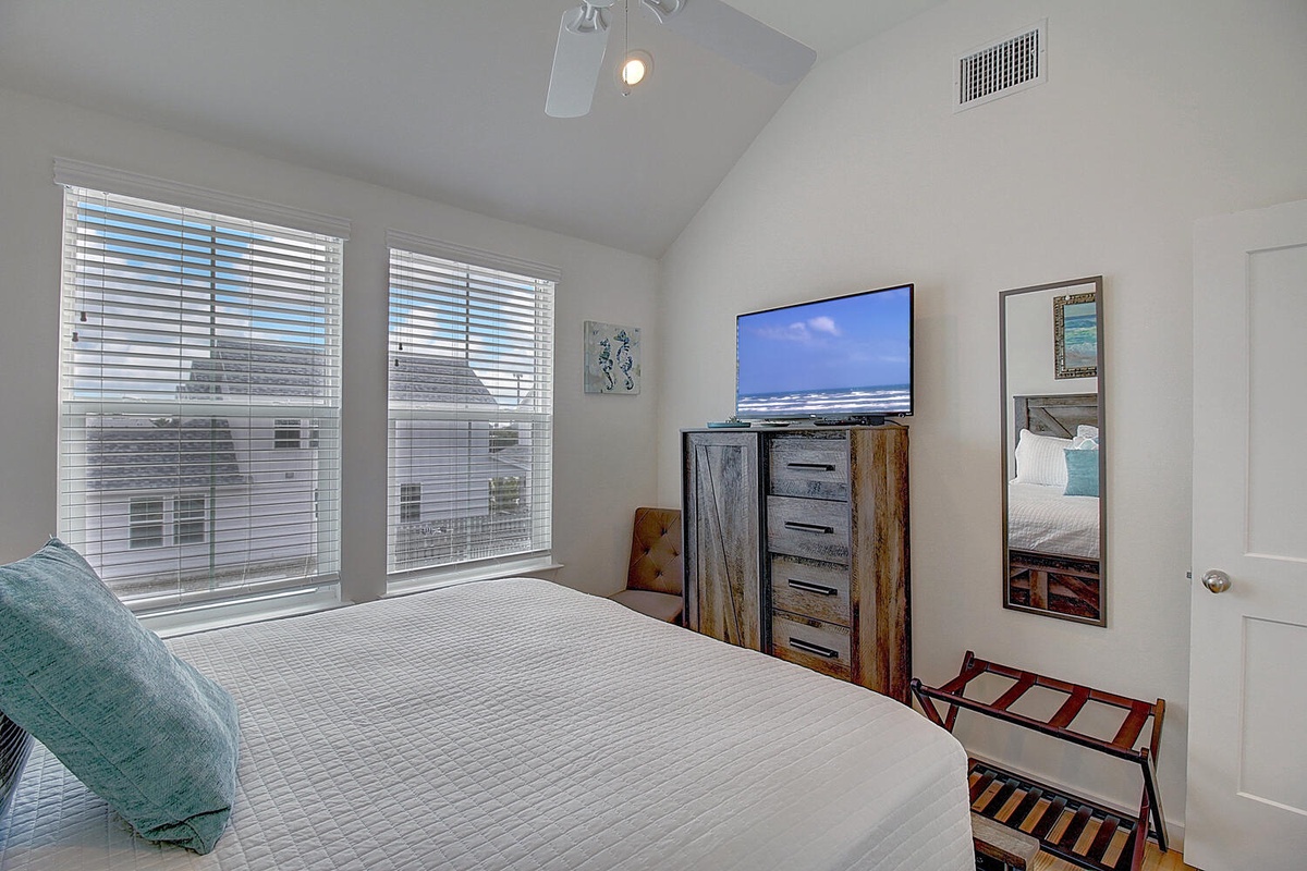 Relax in your bright bedroom with vaulted ceilings, cozy bedding, and modern entertainment setup for comfortable evenings.