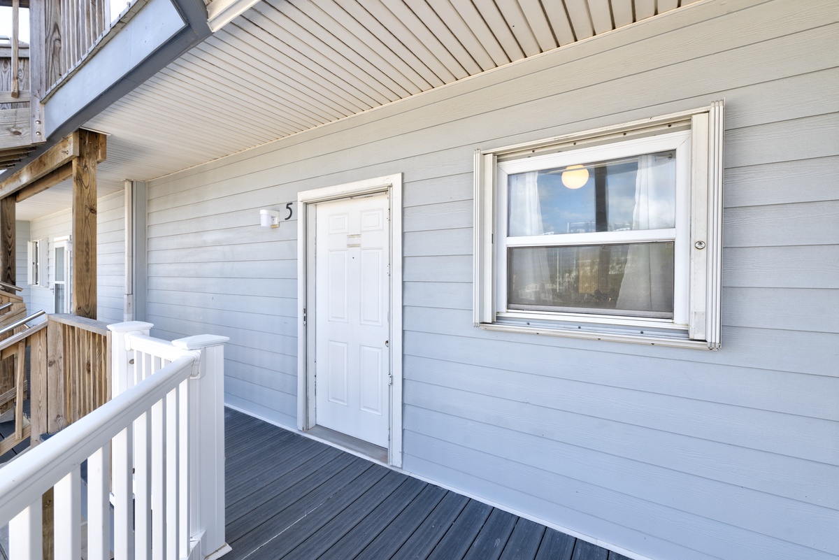 Private entrance to your cozy retreat, where blue wooden siding and a covered porch create a welcoming arrival.