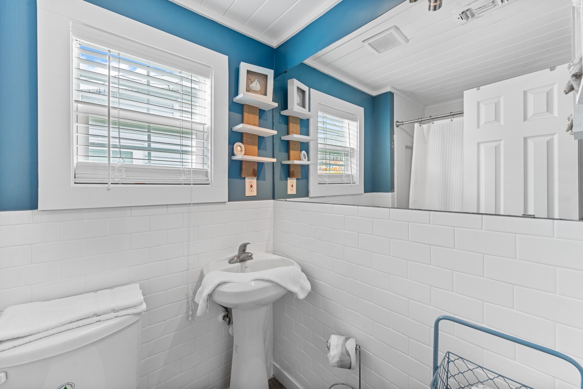Refresh in your bright bathroom with cheerful blue walls, classic subway tiles, and thoughtful touches like floating shelves and fresh towels.