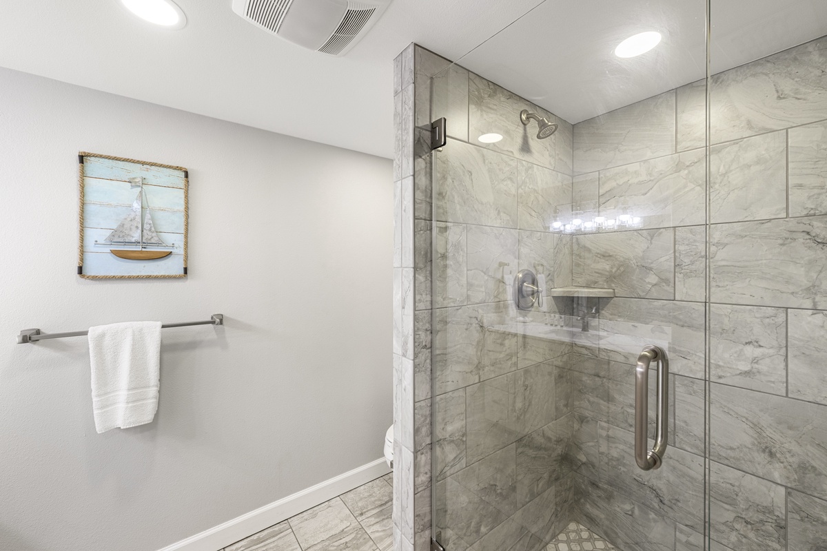 Step into your luxurious marble-tiled shower with a spacious glass enclosure and elegant nautical touches that make every morning feel like a spa retreat.