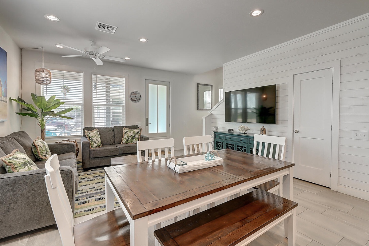 Relax in your beautifully designed open-concept living space, where coastal charm meets modern comfort with tropical pillows and shiplap walls.