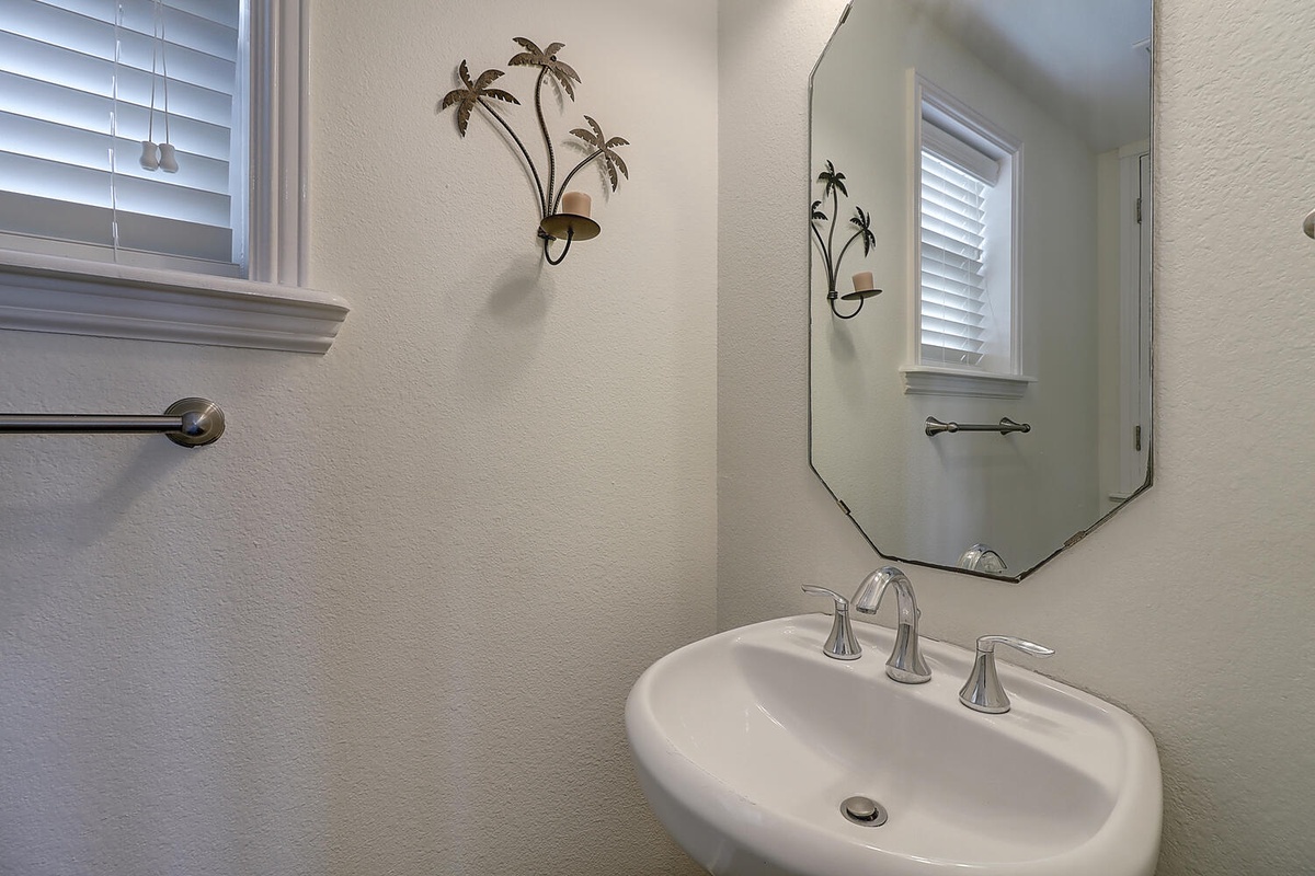 Start your mornings in this thoughtfully designed bathroom with tropical palm accents and natural light streaming through plantation shutters.