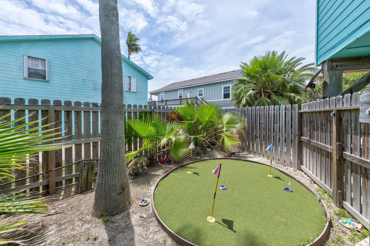 A private putting green nestled in your backyard, complete with palm trees and tropical landscaping—perfect for practicing your swing or enjoying friendly competition under sunny skies.
