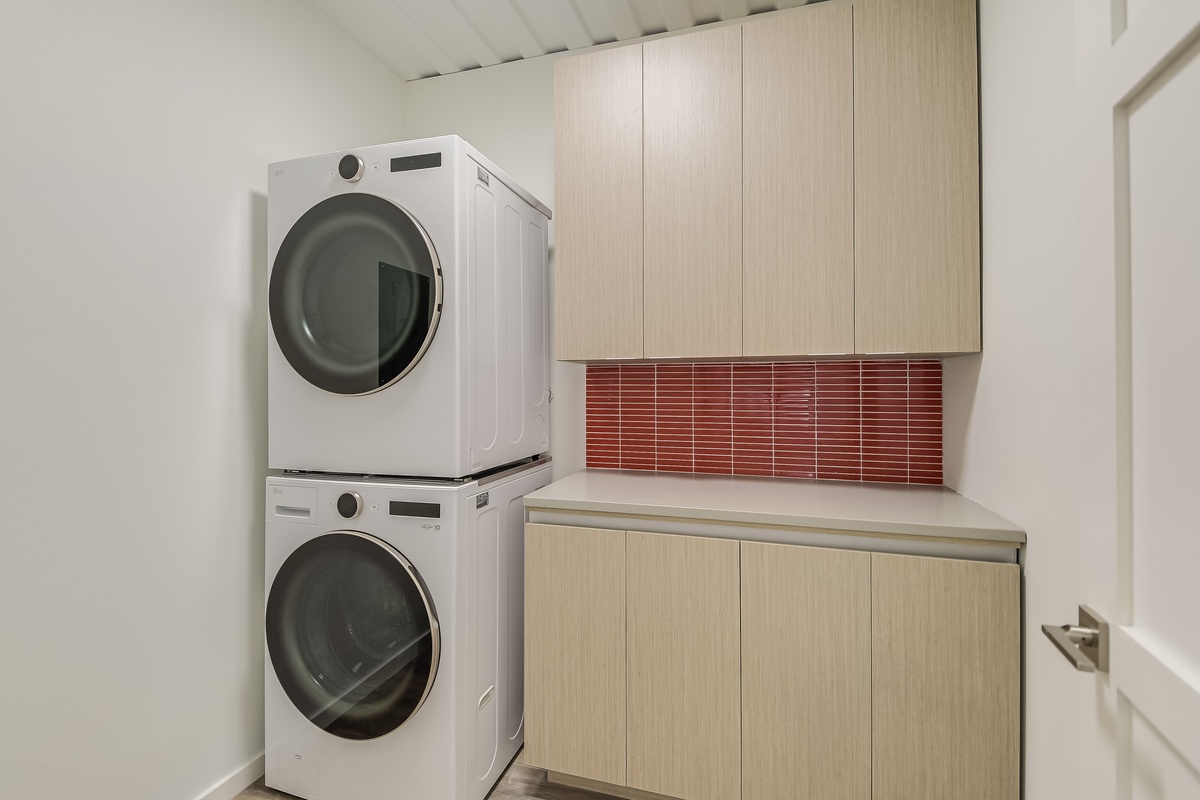 Your dedicated laundry room features modern machines and ample cabinet storage for effortless care of your belongings.