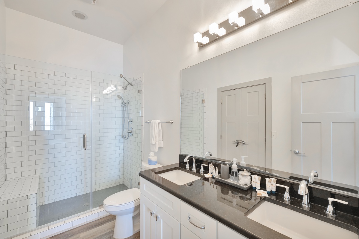 Step into your pristine bathroom featuring a spacious glass shower, elegant dual vanity, and crisp white subway tile throughout.