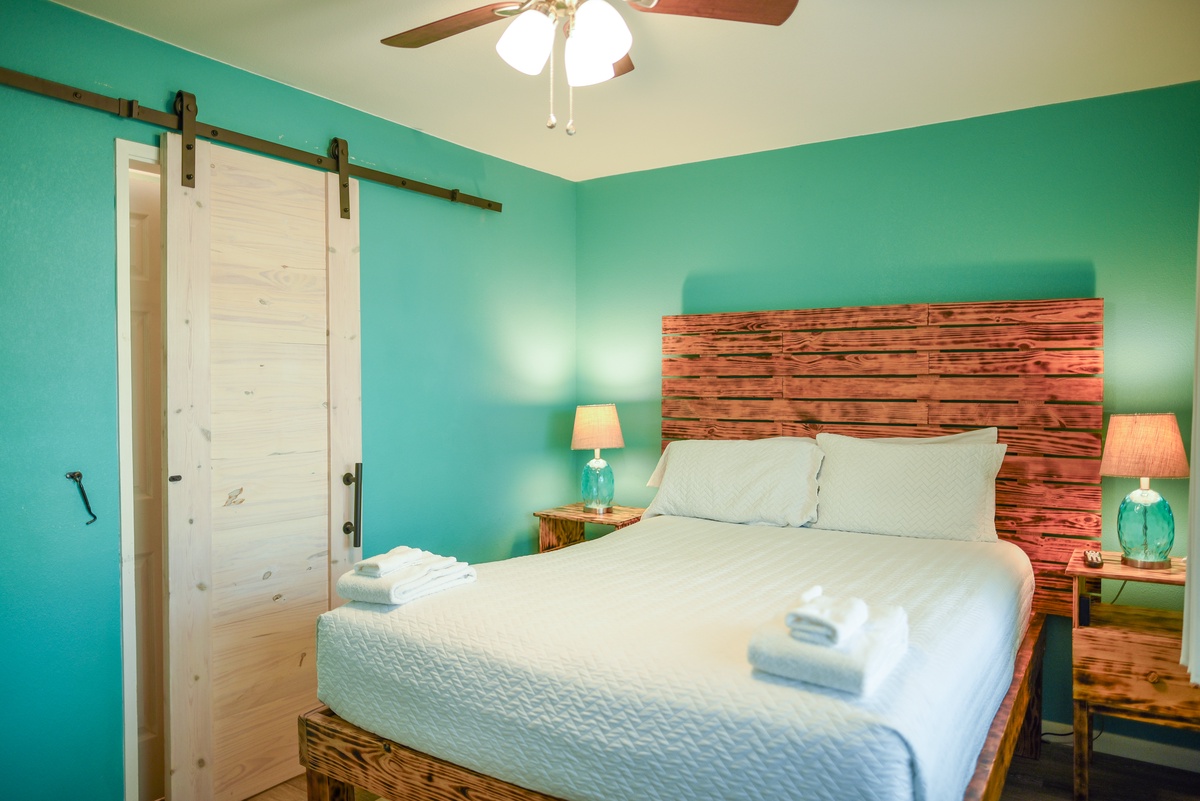 Drift off to sleep in your cozy turquoise retreat, where rustic barn doors and warm wood accents create the perfect peaceful escape.