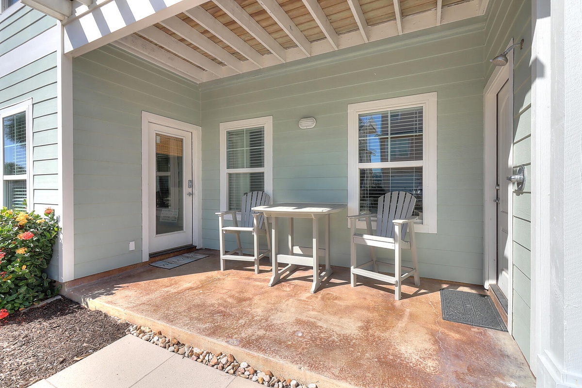 Step onto your private covered patio where morning coffee tastes better in coastal air, surrounded by charming details and peaceful garden views.