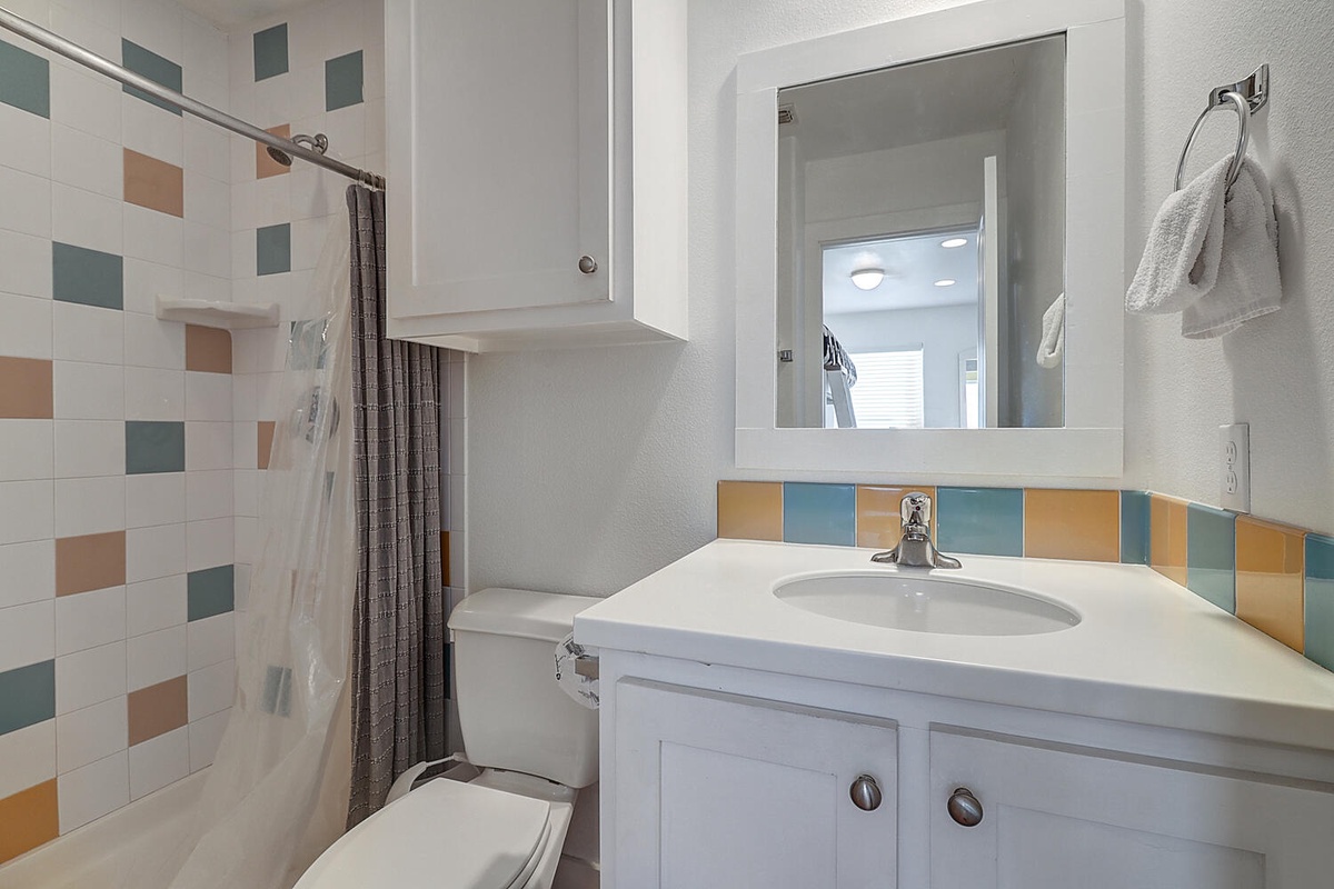 Step into your bright, colorful bathroom featuring cheerful tiled accents and a refreshing shower-tub combo for your relaxing getaway.