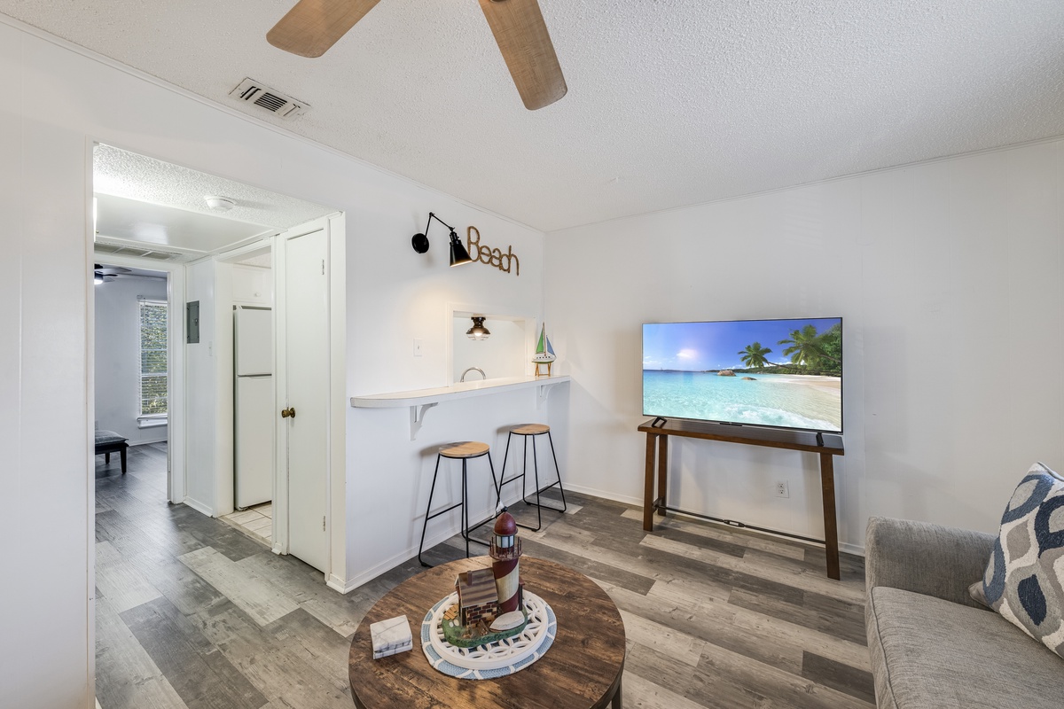 Relax in your bright living space with coastal vibes, complete with breakfast bar, large TV, and modern comfort.