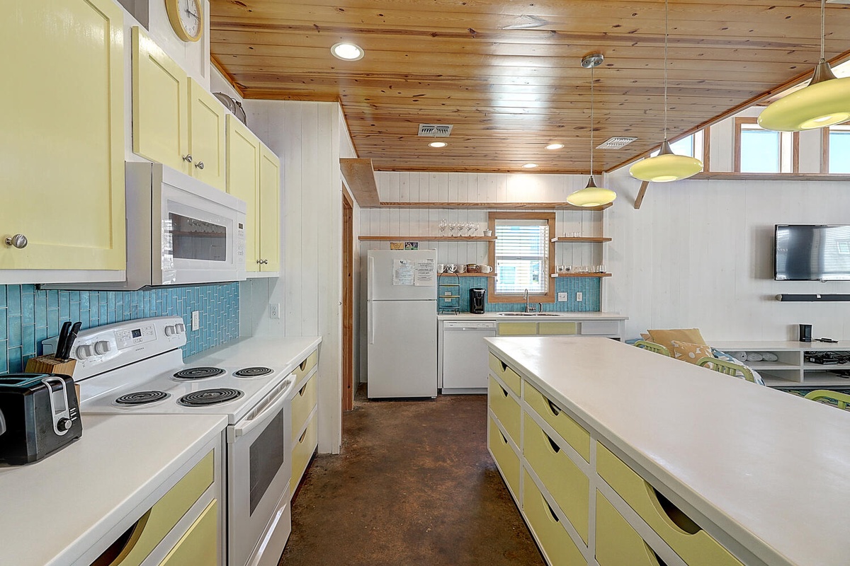 Your cheerful retro kitchen awaits with sunny yellow cabinets, turquoise tile backsplash, and all the amenities to whip up memorable meals.