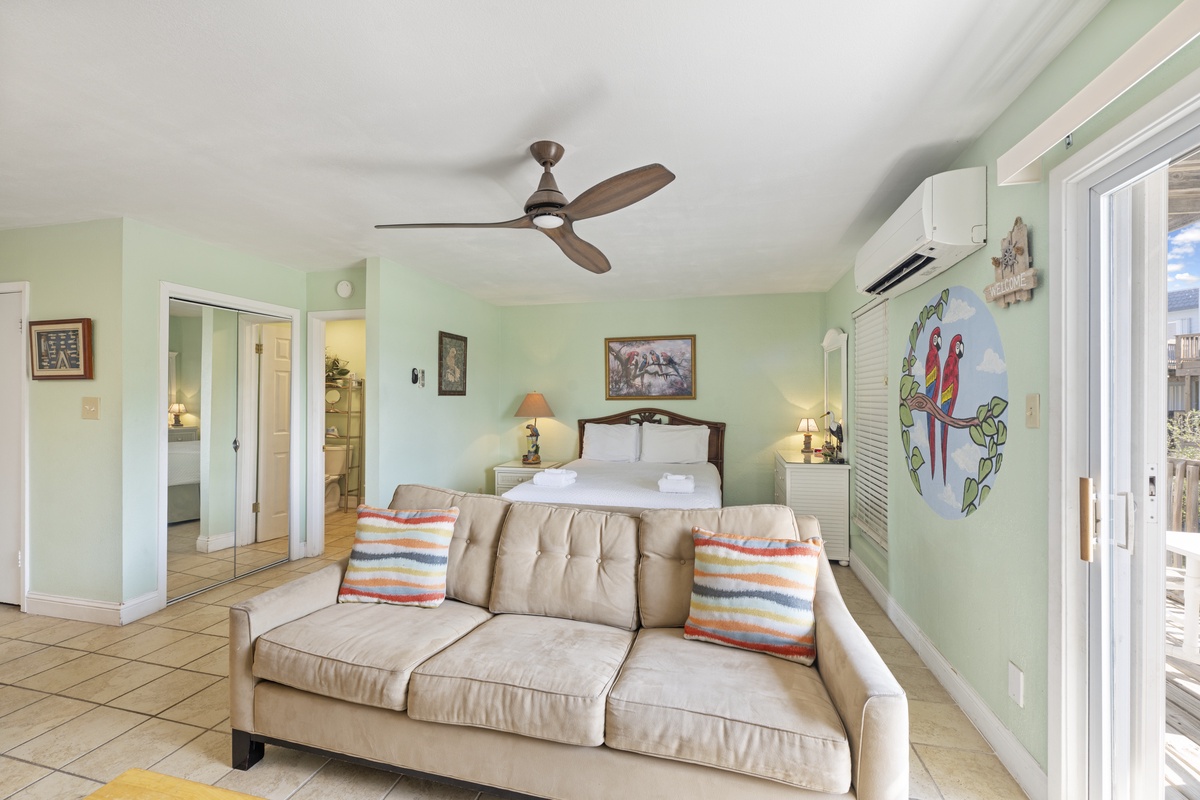 Relax in this tropical studio where vibrant parrot art and soothing green walls create your perfect island retreat.
